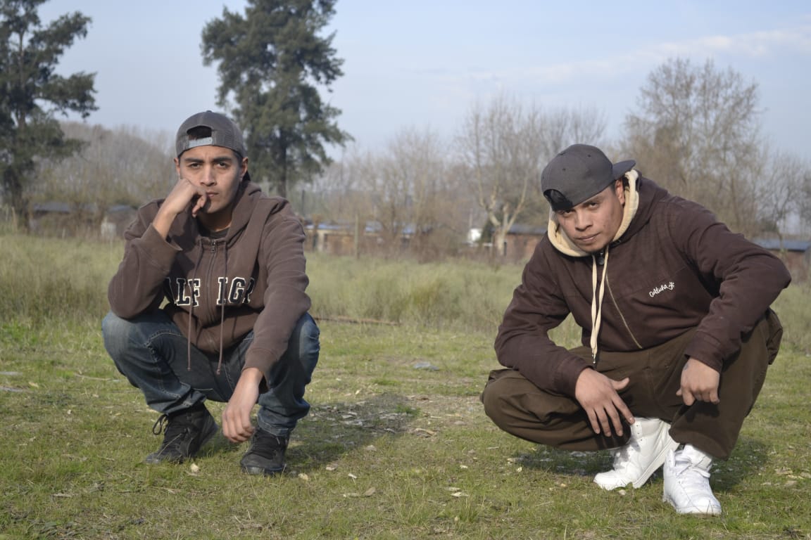 Members of Eskina Qom sitting on some grass.