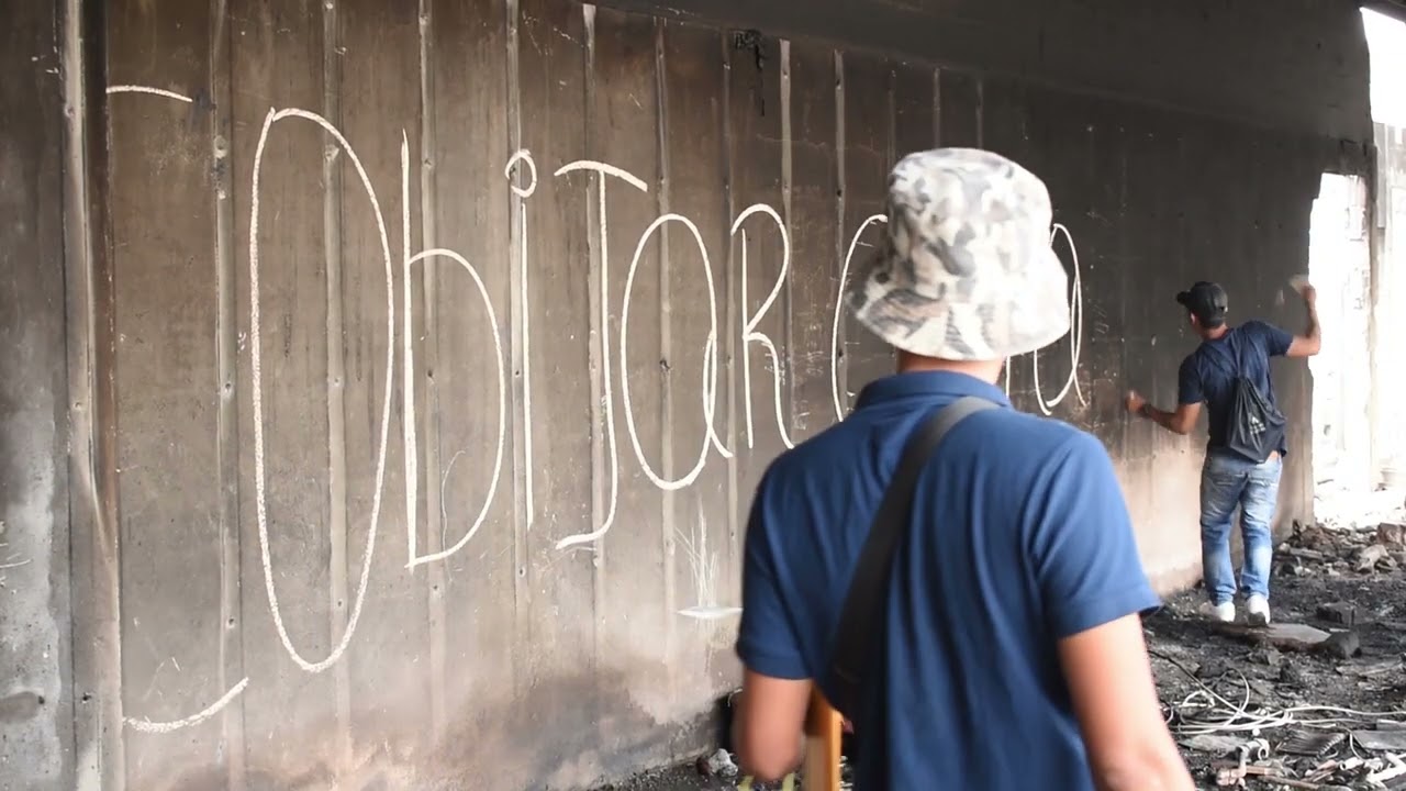 Men chalking slogans in the ruins of the Dollar City shopping centre.