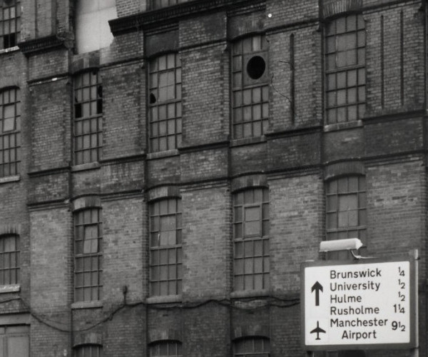 View of a road sign in front of an abandoned mill.