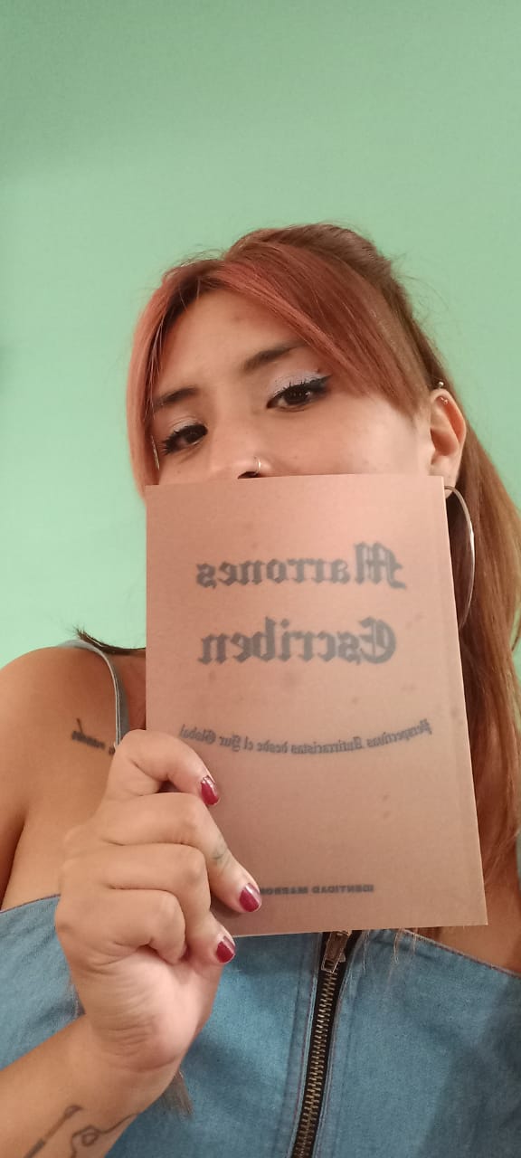 America Canela, one of the authors, shows her book against her skin. 