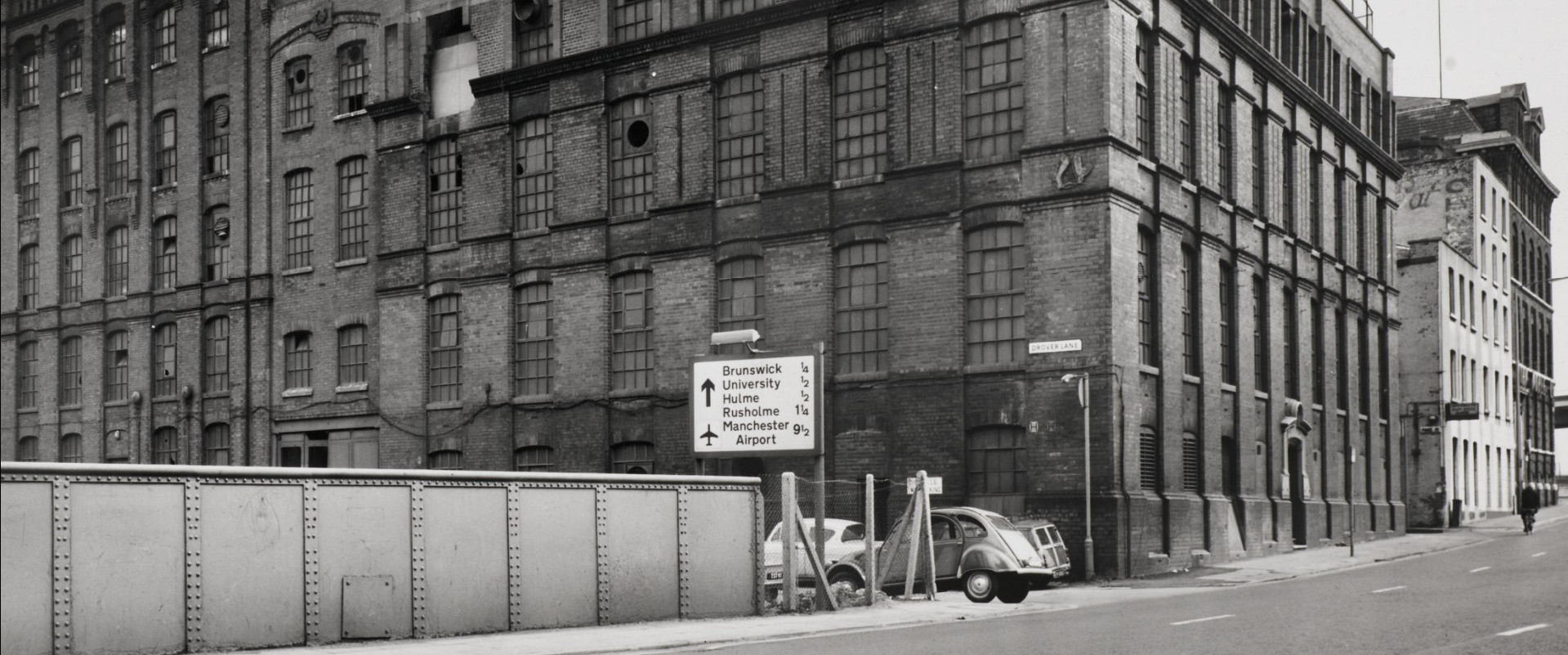 View of a road sign in front of an abandoned mill.