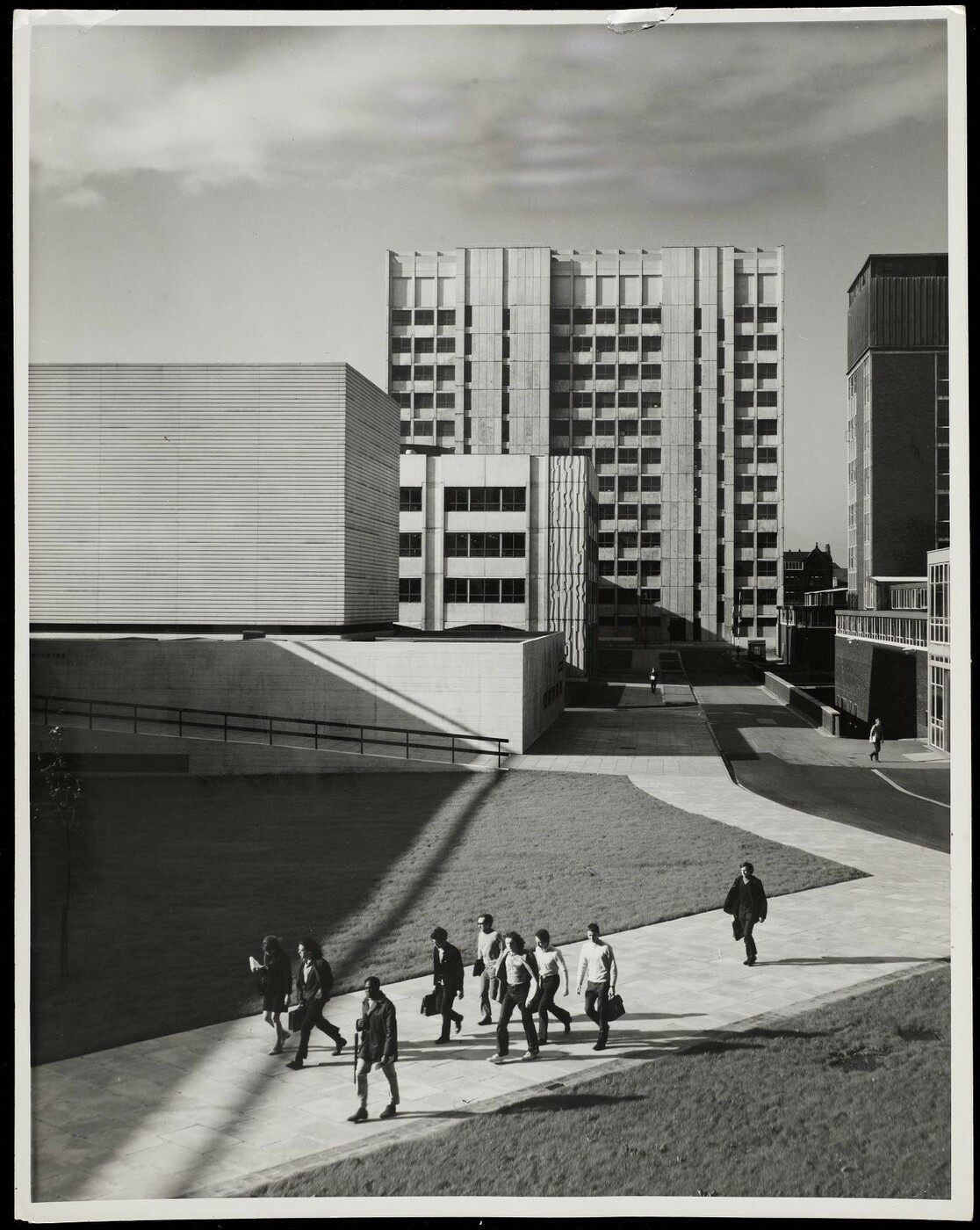 Students walking along a path in the foreground, with the Ferranti and Faraday buildings behind.