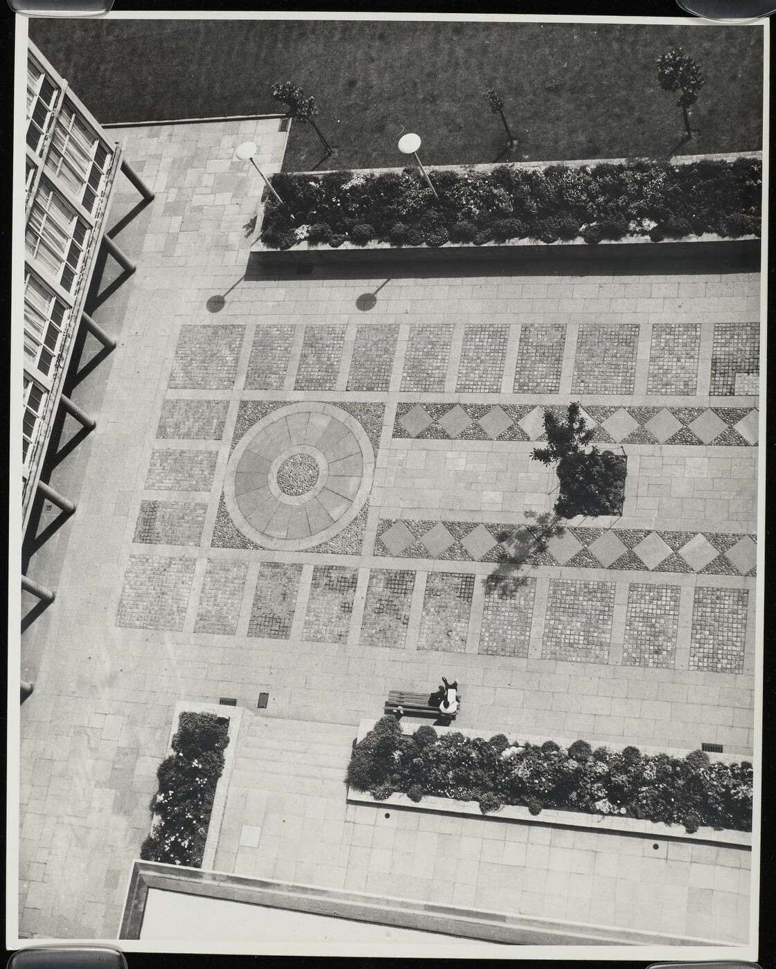 Photograph looking down on a tiled mosaic in a courtyard.