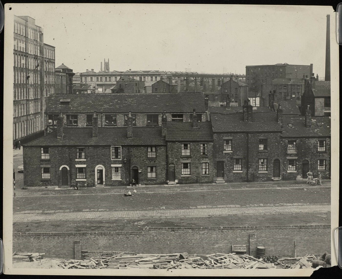 Rows of Victorian terraced housing in poor condition, with mills and warehouses in the background.