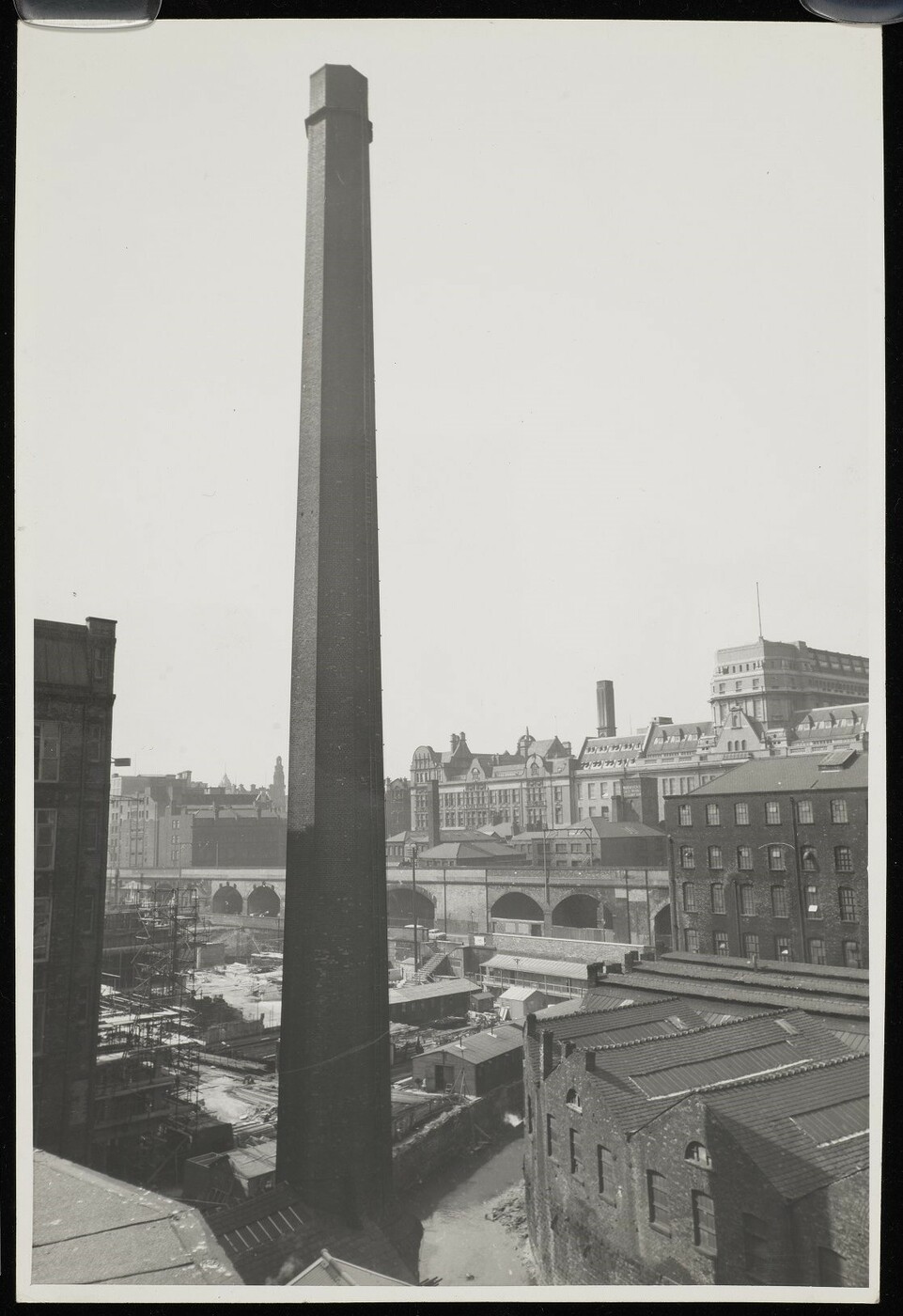 Large mill chimney in the foreground amidst industrial buildings, and the main UMIST building in the background.