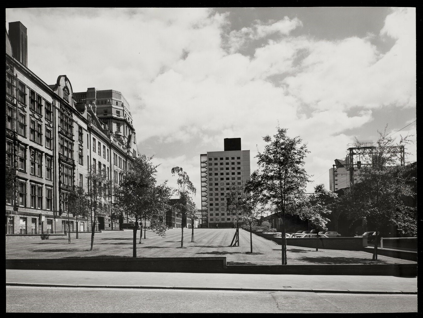 View of Chandos Hall in the distance across a lawn, with the UMIST main building to the left and railway viaducts to the right.