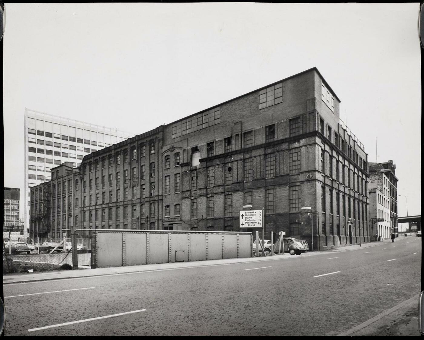 View across a road to the Dunlop Factory, a large Victorian industrial building.