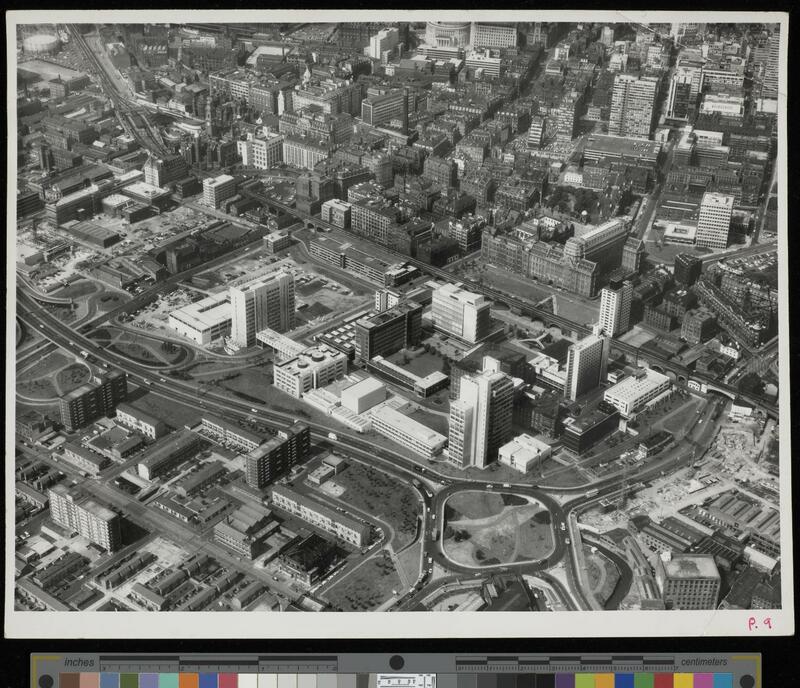 Aerial photograph showing the newly completed UMIST campus at the centre, among the Mancunian Way ring road, new residential units, and the Victorian buildings of central Manchester.  