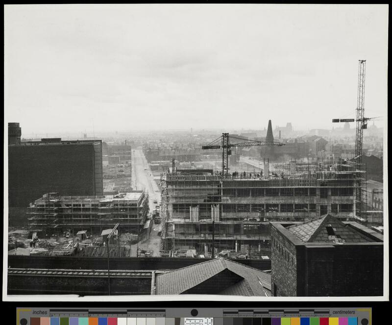 The frame of the Renold building is visible as it's under construction, with older terraced housing in the background. 